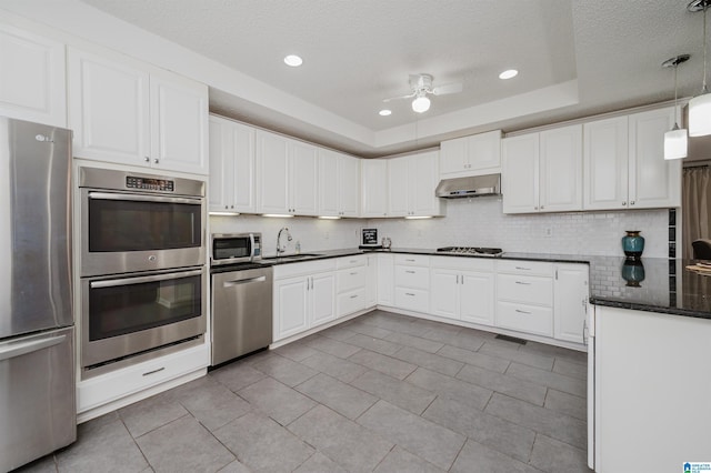 kitchen with a raised ceiling, sink, light tile patterned flooring, white cabinetry, and stainless steel appliances