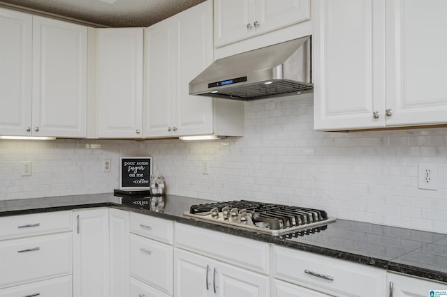 kitchen featuring ventilation hood, stainless steel gas stovetop, white cabinetry, and backsplash