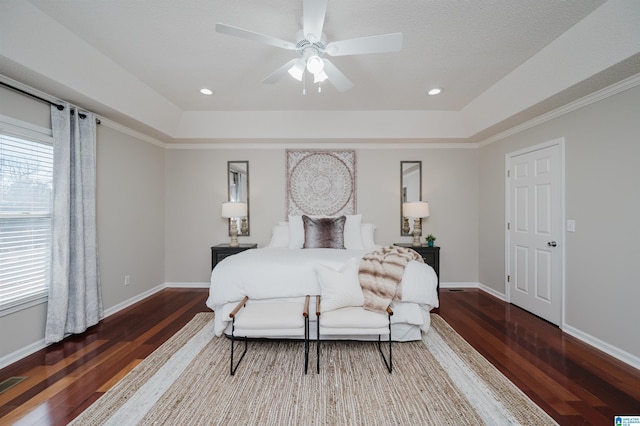 bedroom with ceiling fan, multiple windows, and a tray ceiling