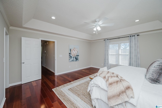 bedroom featuring ceiling fan, dark hardwood / wood-style floors, ornamental molding, a textured ceiling, and a tray ceiling