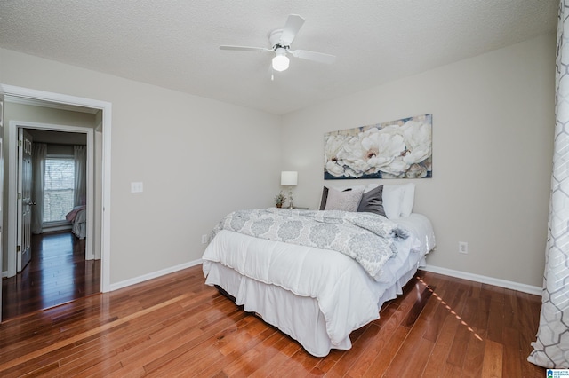 bedroom featuring ceiling fan, hardwood / wood-style floors, and a textured ceiling