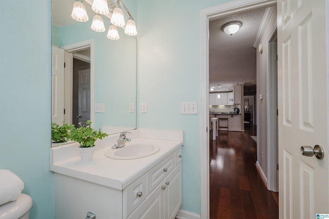 bathroom featuring vanity, a textured ceiling, hardwood / wood-style flooring, a notable chandelier, and toilet