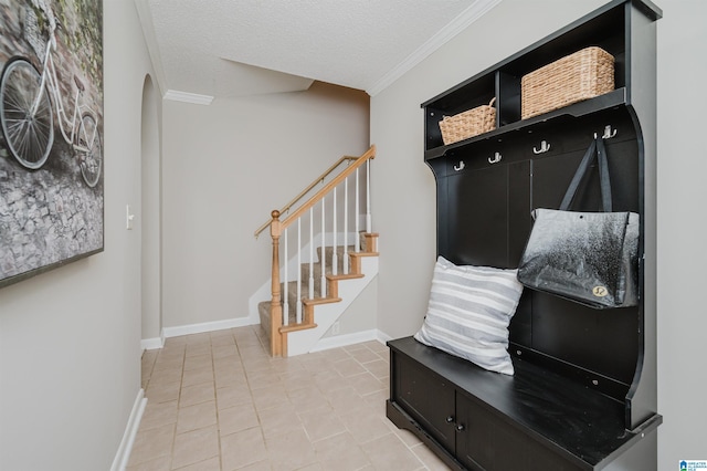 mudroom with tile patterned floors, crown molding, and a textured ceiling