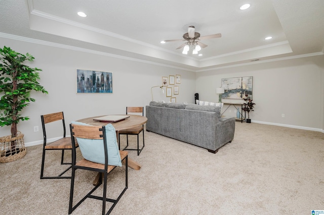 carpeted living room with a tray ceiling, ceiling fan, and crown molding