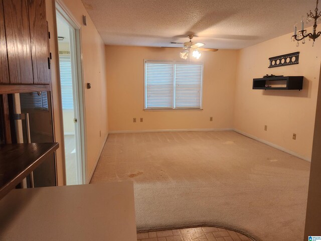 interior space featuring ceiling fan, light carpet, and a textured ceiling