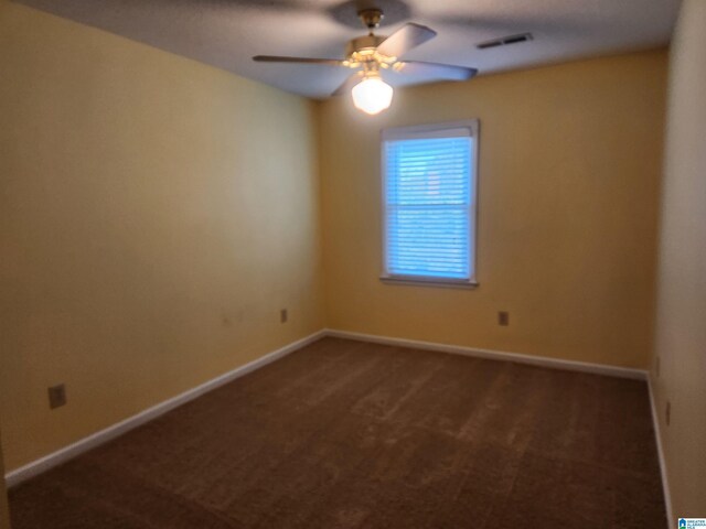 spare room with dark carpet and ceiling fan