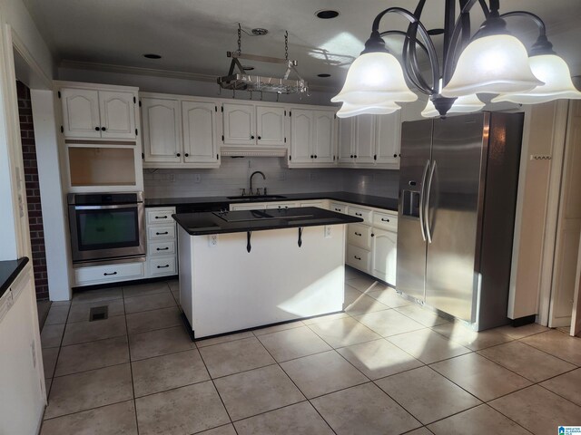 kitchen featuring decorative backsplash, appliances with stainless steel finishes, sink, a center island, and white cabinetry