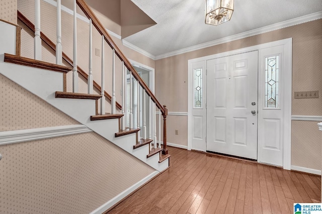 entrance foyer featuring a chandelier, hardwood / wood-style flooring, plenty of natural light, and ornamental molding