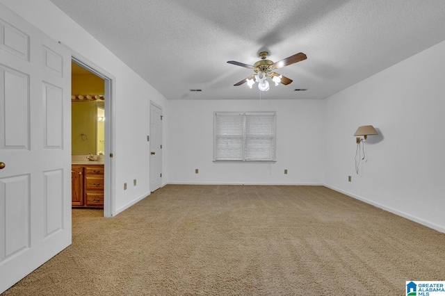 unfurnished bedroom with carpet flooring, ensuite bathroom, ceiling fan, and a textured ceiling