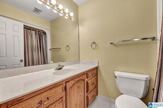 bathroom with toilet, vanity, and tile patterned floors