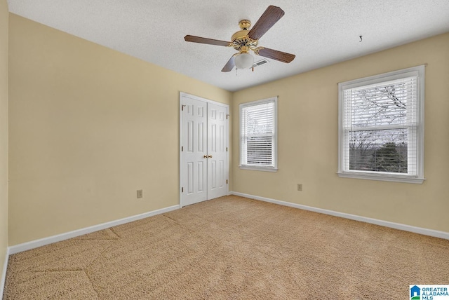 interior space featuring ceiling fan, carpet floors, a textured ceiling, and a closet