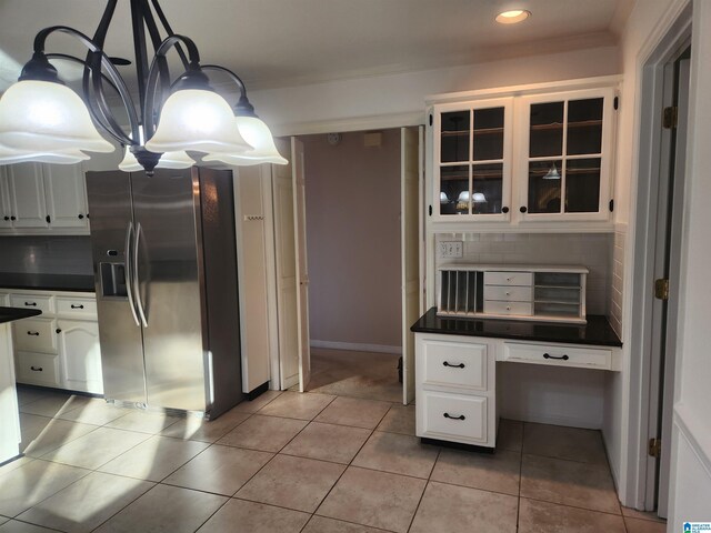 kitchen with stainless steel fridge, tasteful backsplash, light tile patterned floors, pendant lighting, and white cabinets