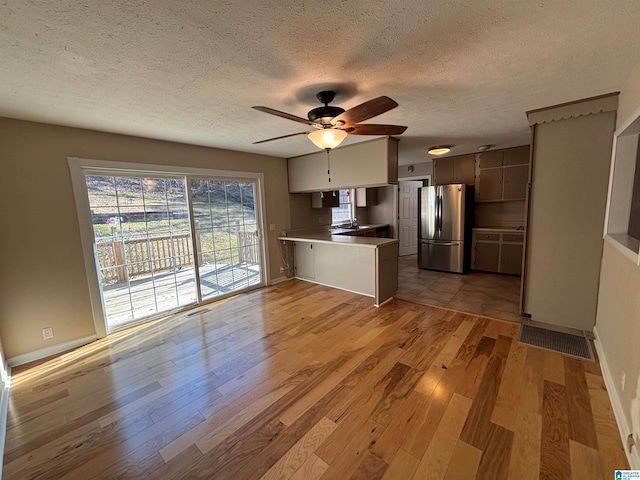 kitchen featuring kitchen peninsula, stainless steel fridge, a textured ceiling, ceiling fan, and light hardwood / wood-style floors