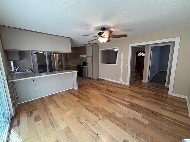 kitchen featuring stainless steel fridge, range with electric cooktop, a textured ceiling, sink, and light hardwood / wood-style flooring