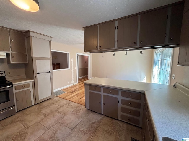 kitchen featuring a textured ceiling, stainless steel range with electric stovetop, gray cabinetry, and exhaust hood