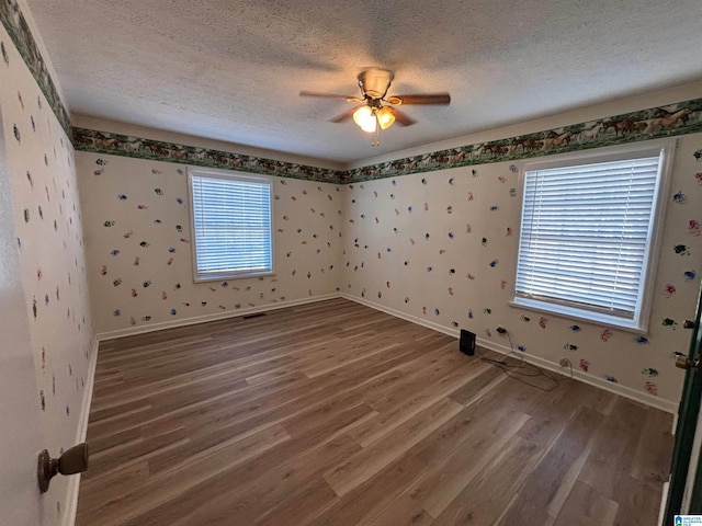 empty room with ceiling fan, hardwood / wood-style floors, and a textured ceiling