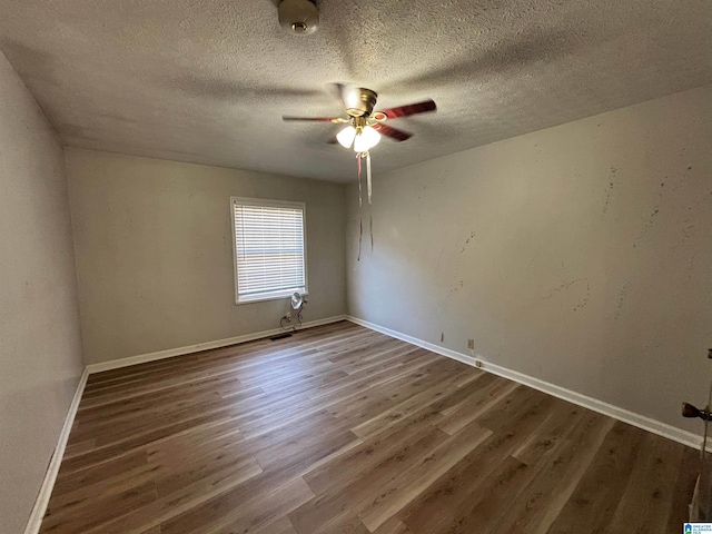 unfurnished room featuring dark hardwood / wood-style floors, ceiling fan, and a textured ceiling