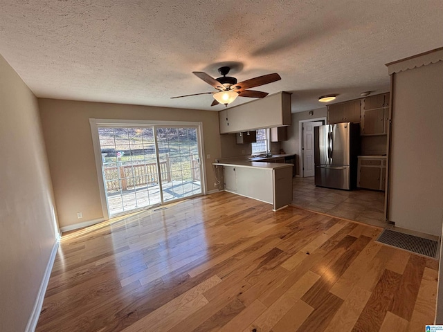 kitchen featuring stainless steel refrigerator, ceiling fan, kitchen peninsula, and light hardwood / wood-style flooring