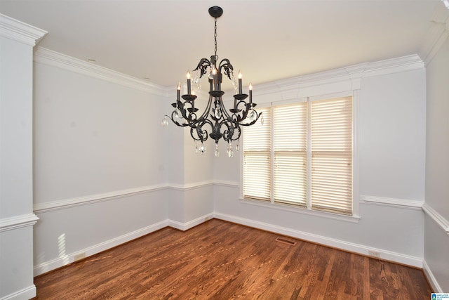 empty room featuring dark hardwood / wood-style flooring, ornamental molding, and a chandelier