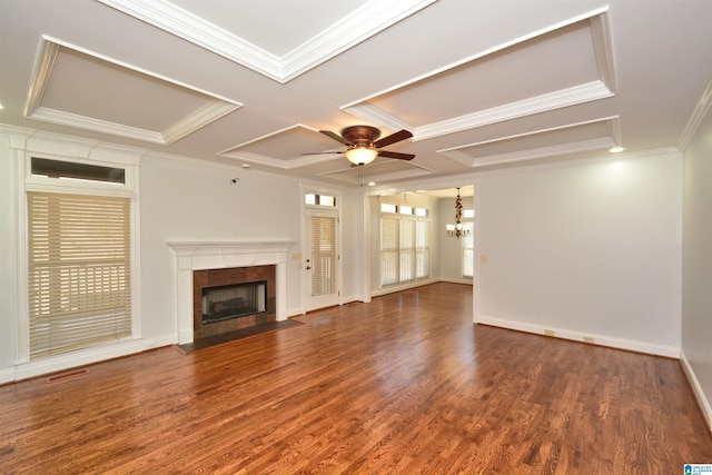 unfurnished living room with dark wood-type flooring, a tile fireplace, coffered ceiling, ceiling fan with notable chandelier, and ornamental molding