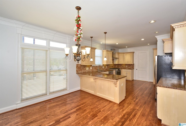 kitchen with pendant lighting, ornamental molding, appliances with stainless steel finishes, kitchen peninsula, and a breakfast bar area