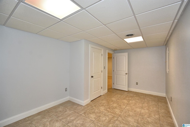 basement with a paneled ceiling and light tile patterned flooring