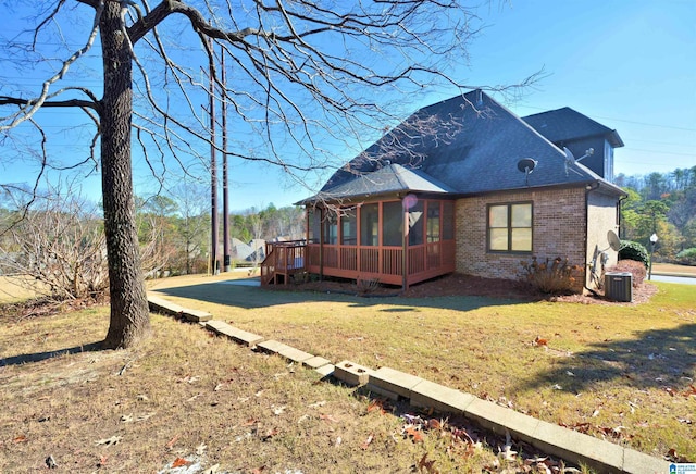 exterior space featuring a lawn, a wooden deck, a sunroom, and central air condition unit