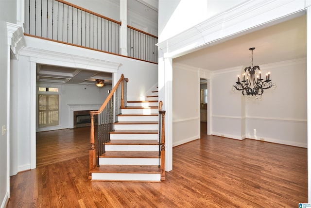 staircase featuring coffered ceiling, crown molding, beamed ceiling, a notable chandelier, and wood-type flooring