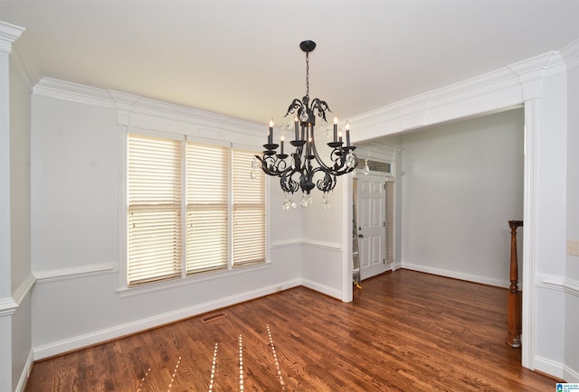 unfurnished dining area with dark hardwood / wood-style flooring, ornamental molding, and an inviting chandelier