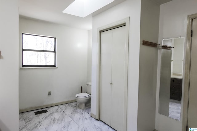 bathroom featuring a skylight and toilet