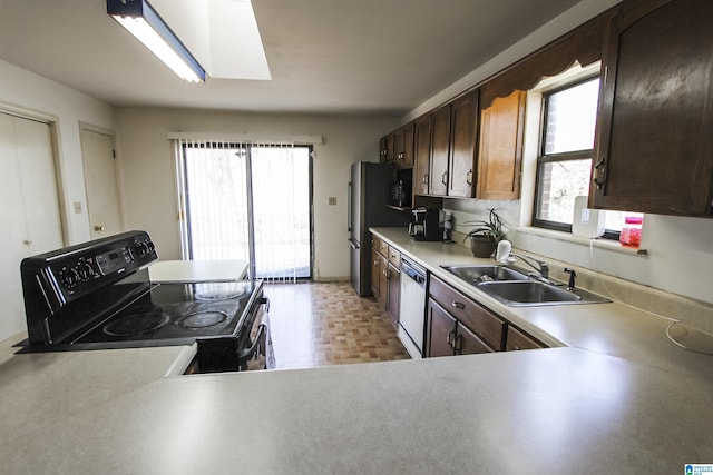 kitchen featuring light parquet floors, sink, a skylight, appliances with stainless steel finishes, and kitchen peninsula