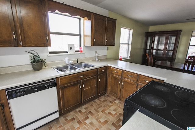 kitchen featuring dishwasher, sink, electric range, dark brown cabinets, and kitchen peninsula