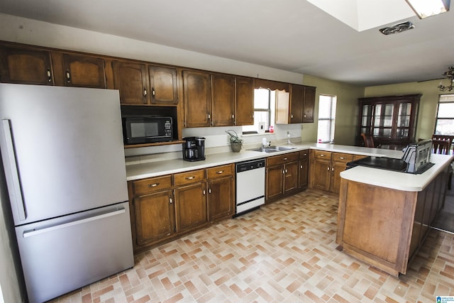 kitchen with stainless steel refrigerator, dark brown cabinetry, dishwasher, sink, and kitchen peninsula