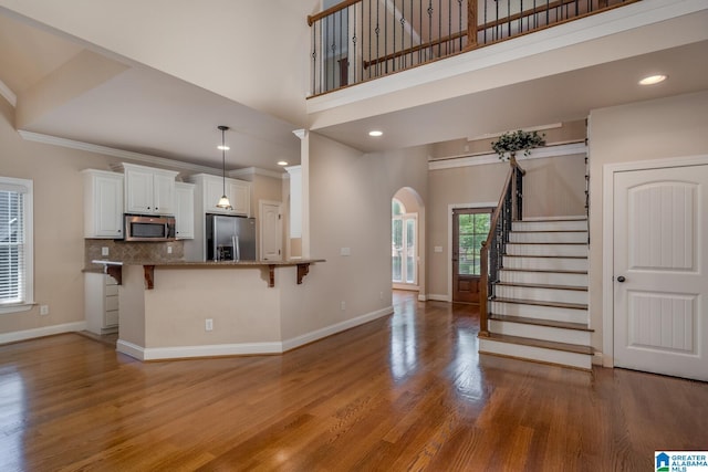 kitchen with backsplash, white cabinets, kitchen peninsula, a breakfast bar area, and stainless steel appliances