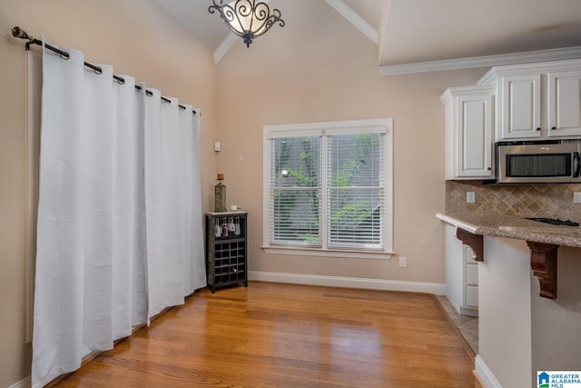 interior space featuring light hardwood / wood-style flooring, vaulted ceiling, and ornamental molding