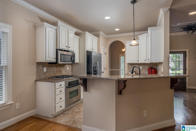 kitchen featuring a kitchen bar, light stone counters, white cabinets, and stainless steel appliances