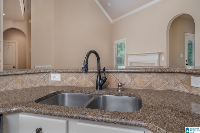 kitchen with backsplash, crown molding, sink, and lofted ceiling