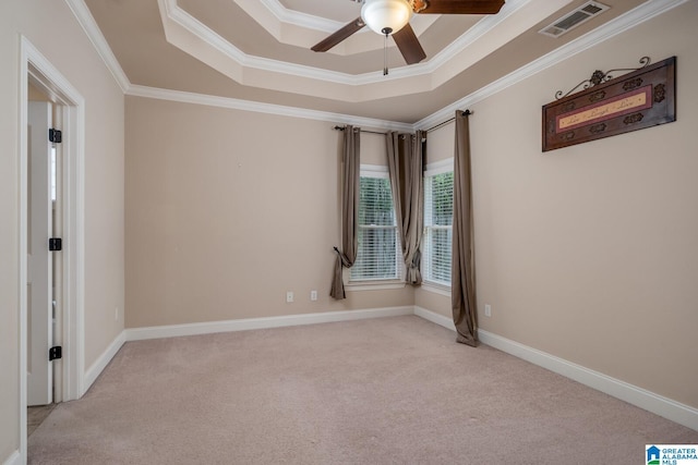 empty room with a raised ceiling, crown molding, ceiling fan, and light carpet