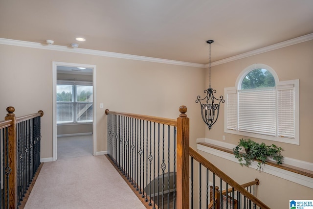 hallway featuring light colored carpet, crown molding, and a chandelier