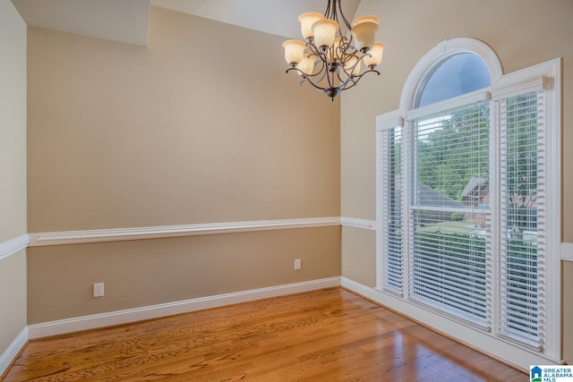 unfurnished room featuring hardwood / wood-style floors and a chandelier