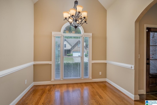 interior space featuring light wood-type flooring, vaulted ceiling, and an inviting chandelier