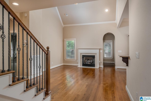 unfurnished living room with wood-type flooring and crown molding