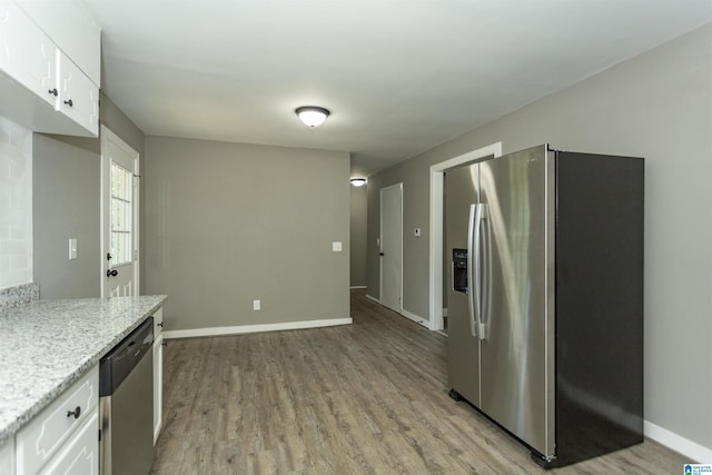 kitchen with light stone countertops, white cabinetry, light hardwood / wood-style flooring, and stainless steel appliances