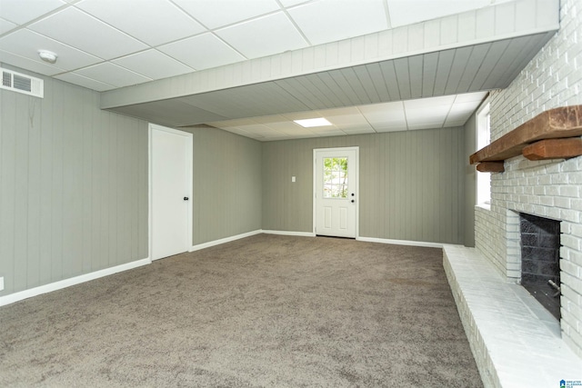 unfurnished living room featuring a paneled ceiling, a fireplace, and carpet