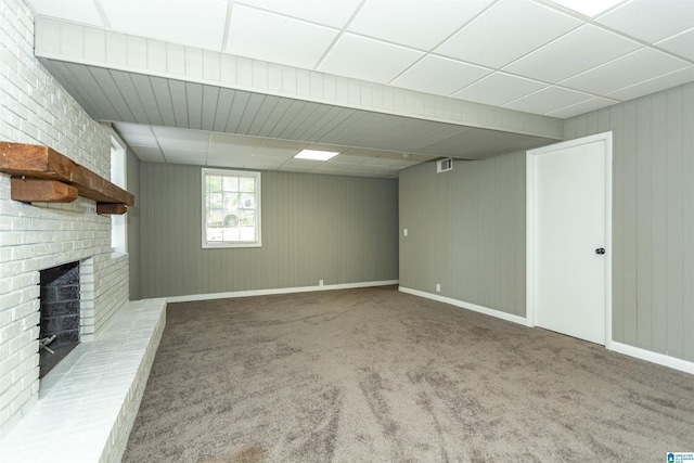 basement featuring a paneled ceiling, carpet floors, and a brick fireplace