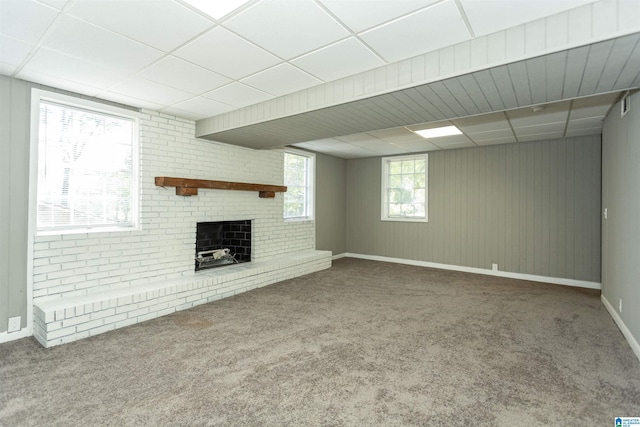 basement with carpet flooring, a drop ceiling, and a brick fireplace