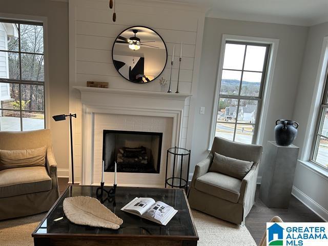 living area featuring ceiling fan, a fireplace, and wood-type flooring