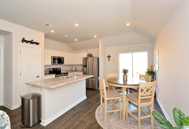 kitchen featuring white cabinets, a kitchen island with sink, appliances with stainless steel finishes, and vaulted ceiling