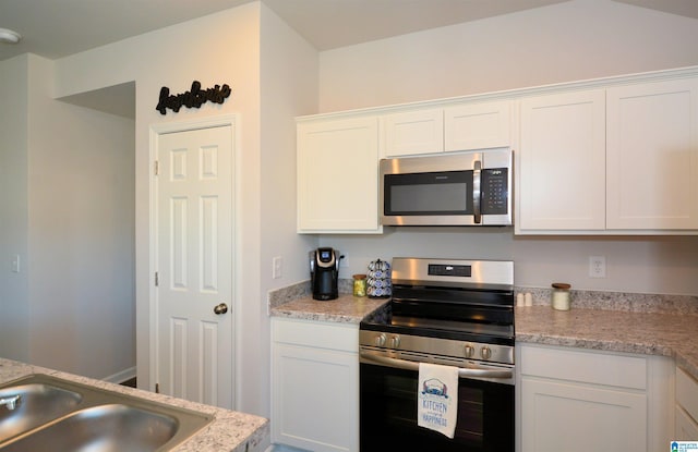 kitchen with light stone countertops, white cabinetry, and stainless steel appliances