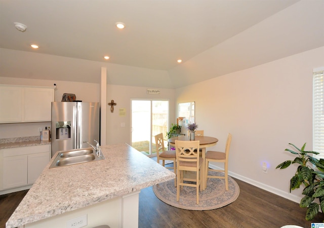 kitchen with stainless steel refrigerator with ice dispenser, sink, white cabinets, lofted ceiling, and an island with sink